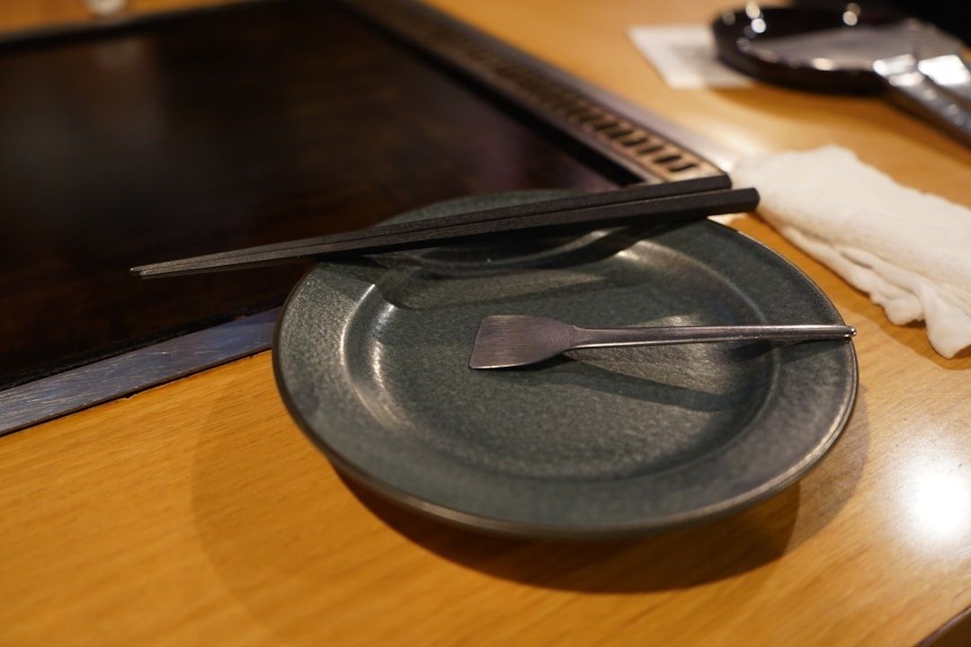 Japanse tafelsetting met donker bord, eetstokjes en kleine vork